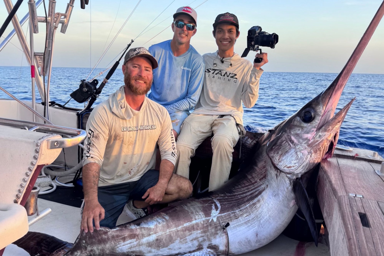 Nick and crew posing with a marlin catch aboard a fishing boat