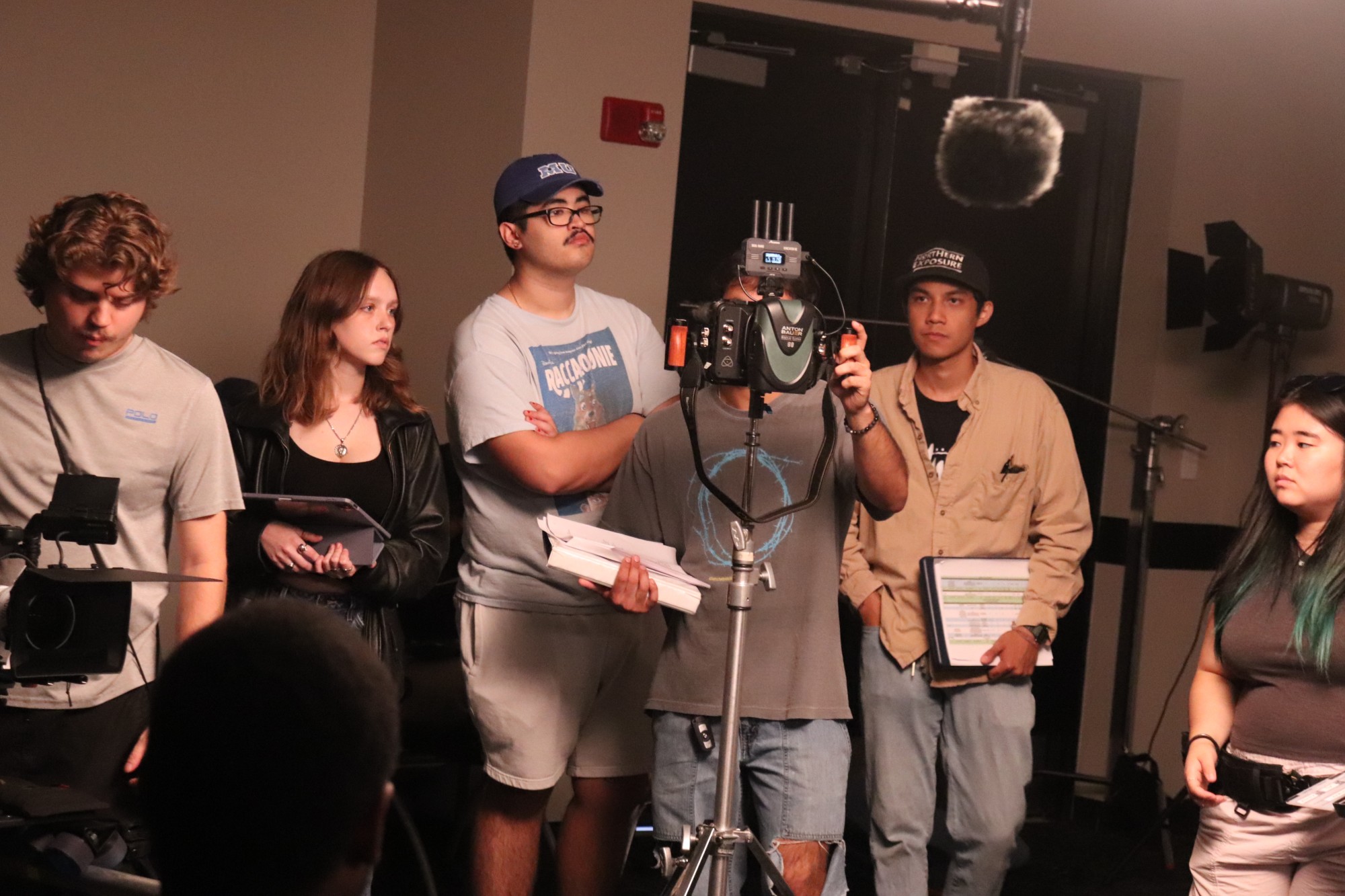 Crew gathered around a camera rig and boom mic checking a shot