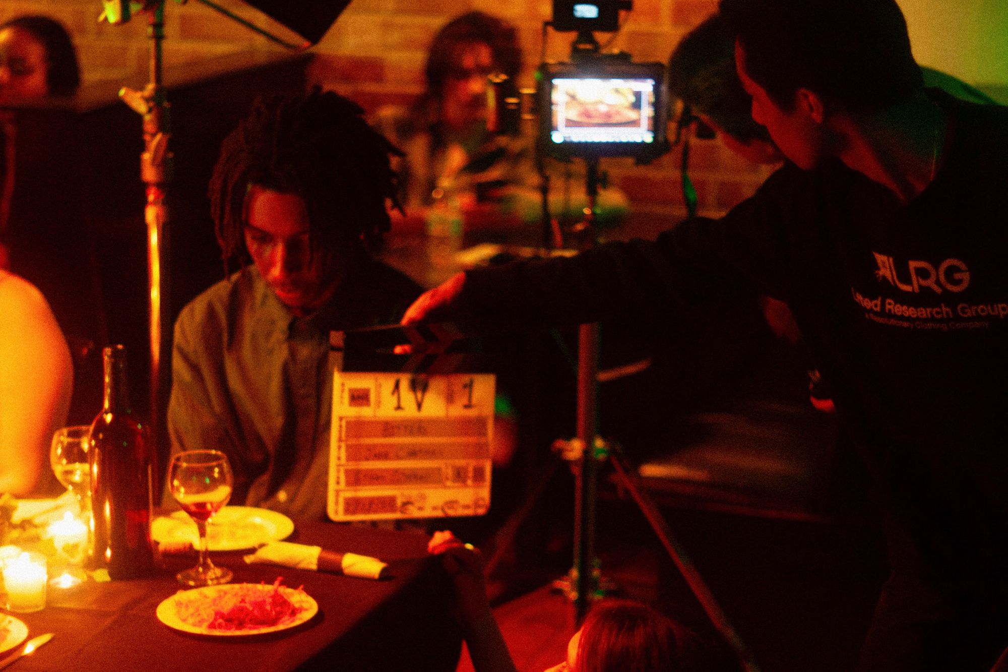 A film slate held beside an actor at a dinner table on set