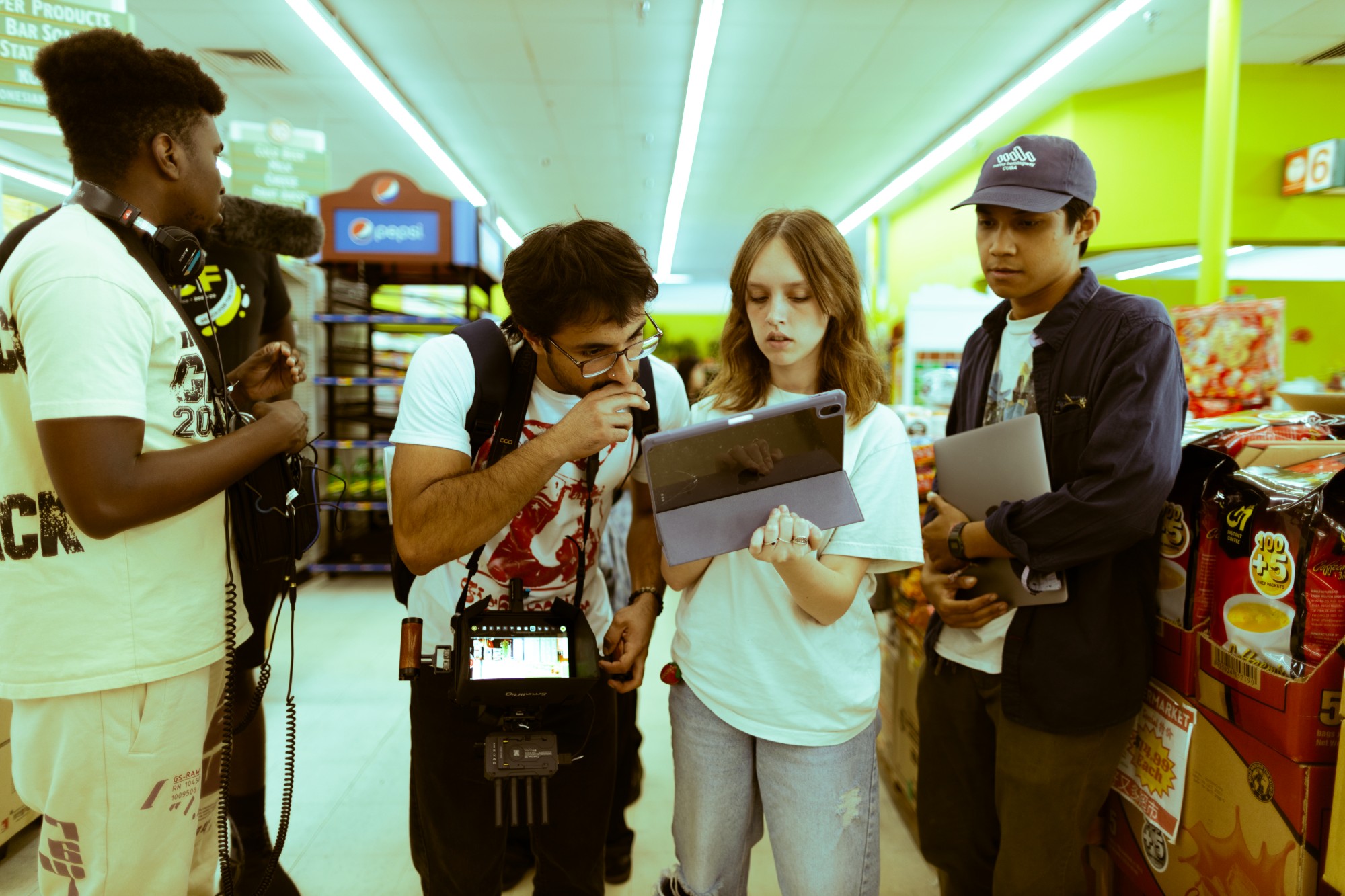 Crew huddled around a monitor reviewing a take on location in a store